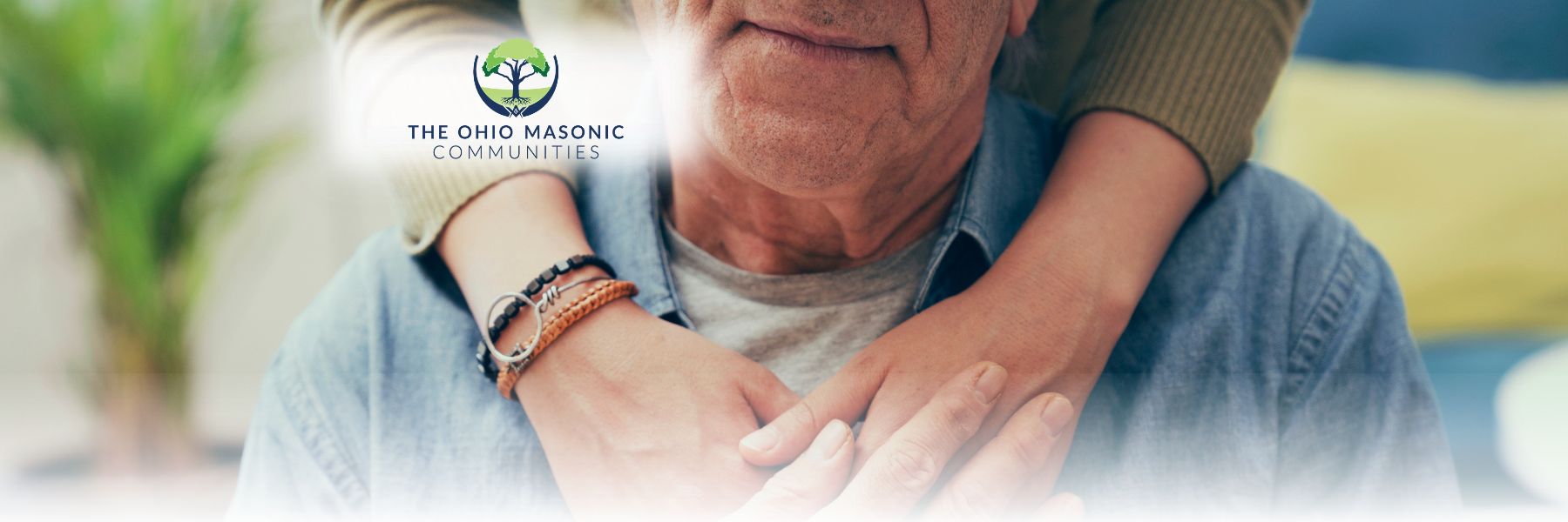 Someone placing their hands on an older adult male to provide comfort