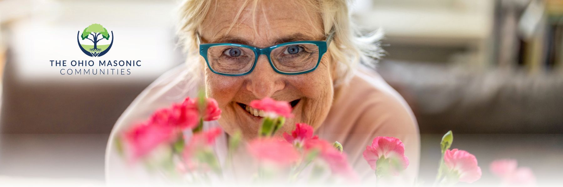 Older adult smiles in front of flowers
