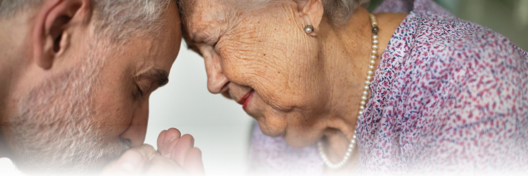 Older adult woman's hand being kissed by loved one