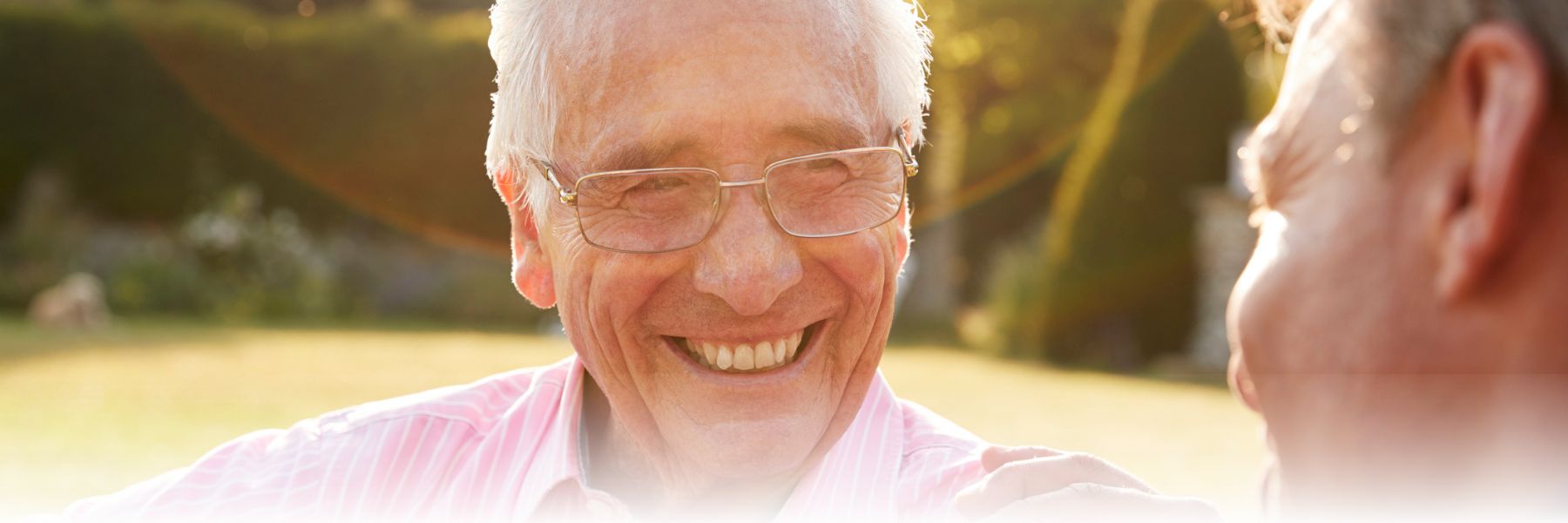 Older adult man laughing outside with friend