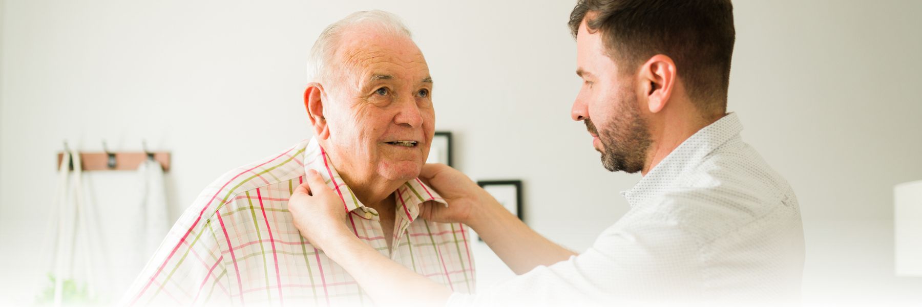 Older adult man with younger man who is helping with daily activities