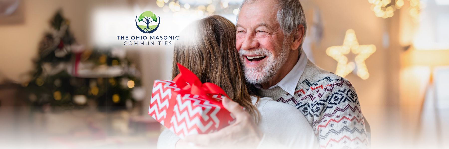 Older adult male embraces female and holds a holiday gift