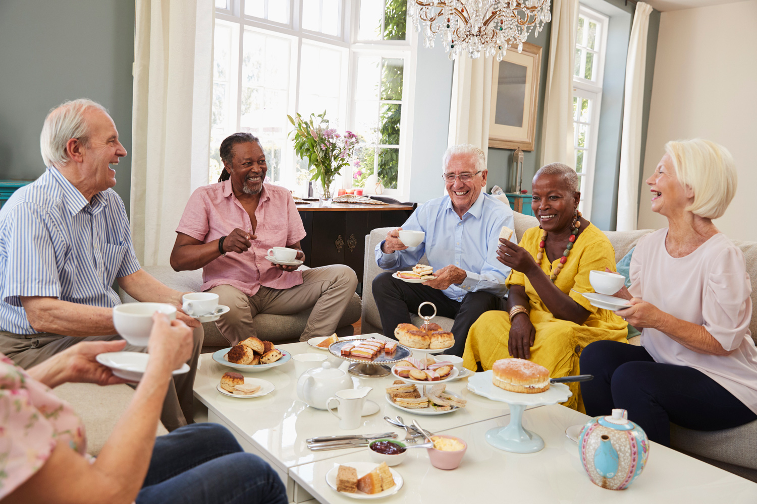 Small group of older adults drinking tea and enjoying desserts together