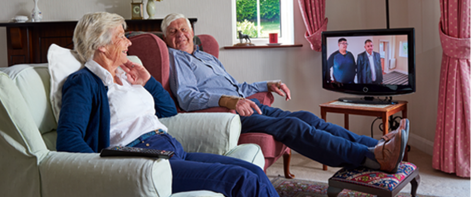 Couple sits and watches television together