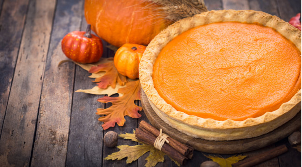 Pumpkin pie next to leaves and pumpkins