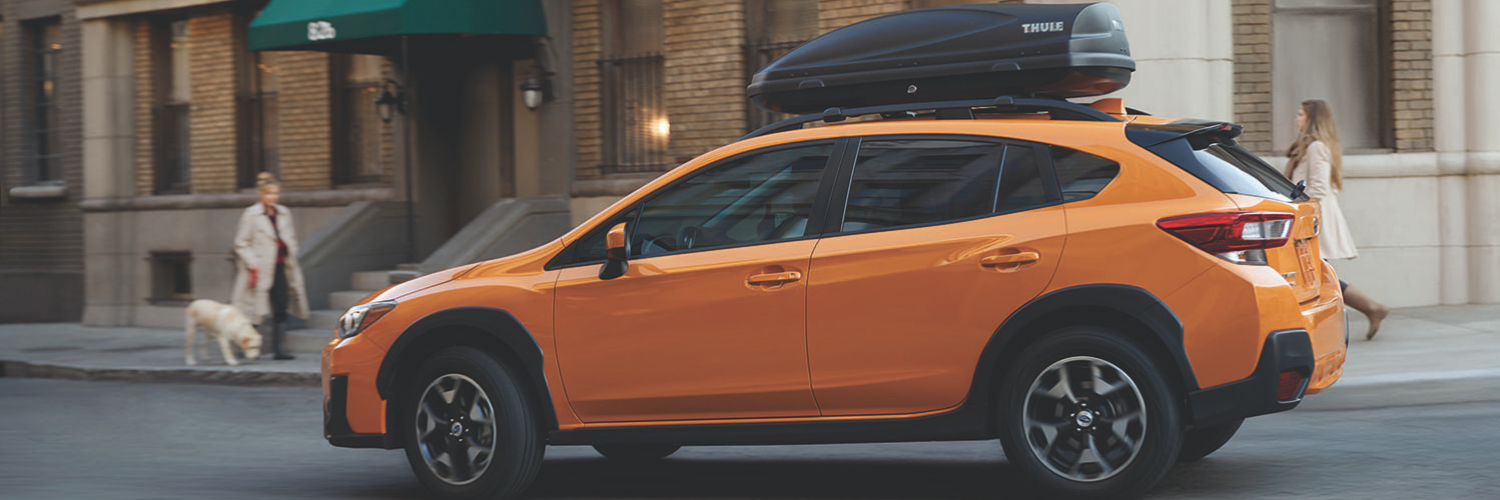 Orange car with overhead storage container on top driving in the city