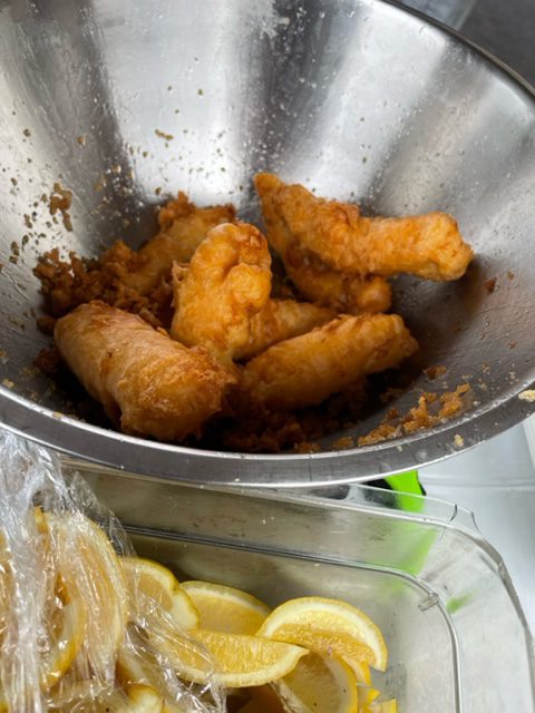 Close-up view of fried fish next to container of sliced lemons