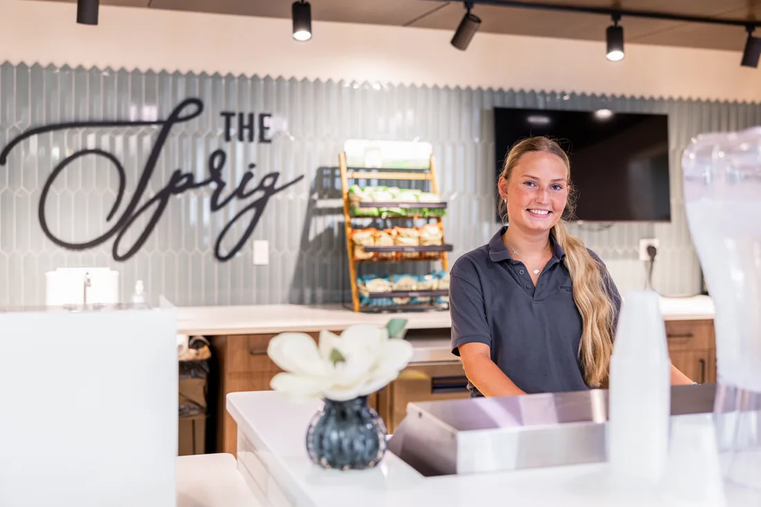 Female cafe worker smiles behind the counter at The Sprig