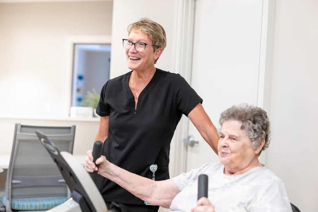 Physical therapist works with a senior female that is using exercise equipment