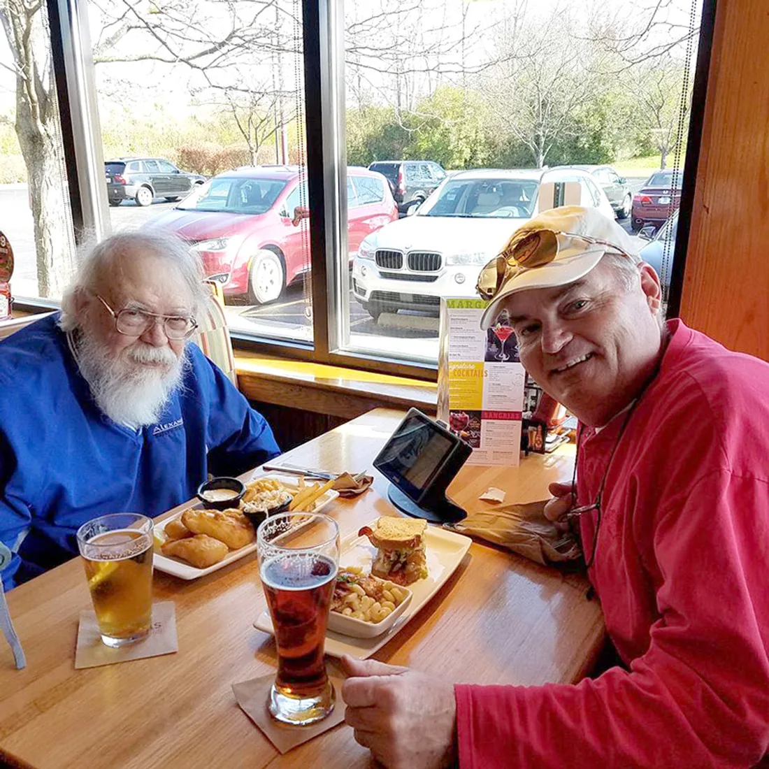 Older adult male dines at a restaurant with an adult male
