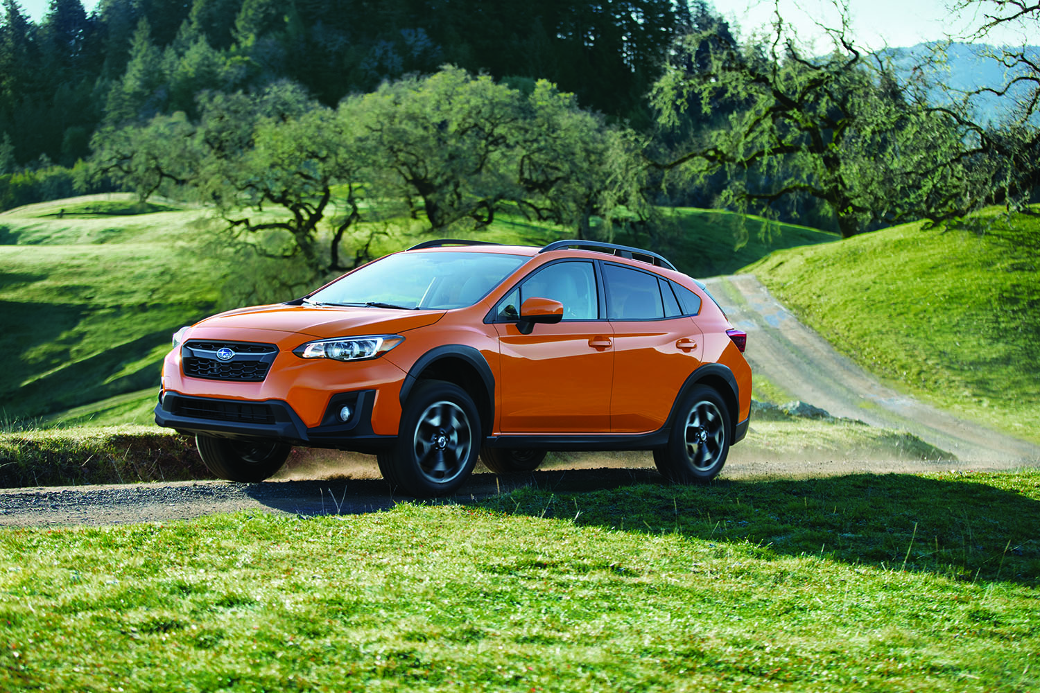 Orange car with overhead storage container on top driving in the country