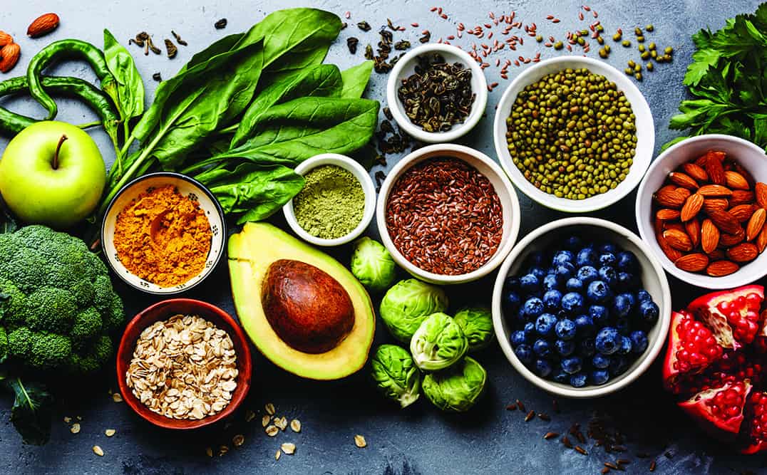 Healthy foods, including an apple, other fruits, grains, nuts, and veggies