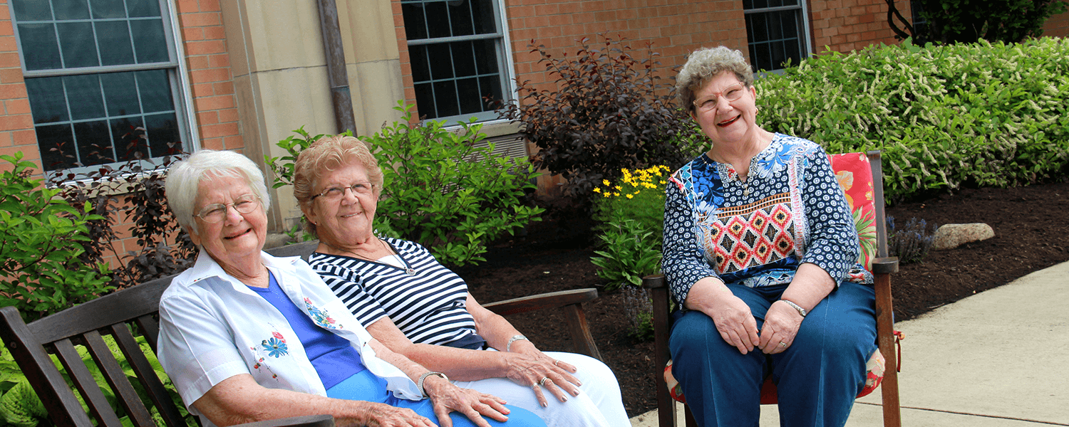 Three older adult females sit together outdoors
