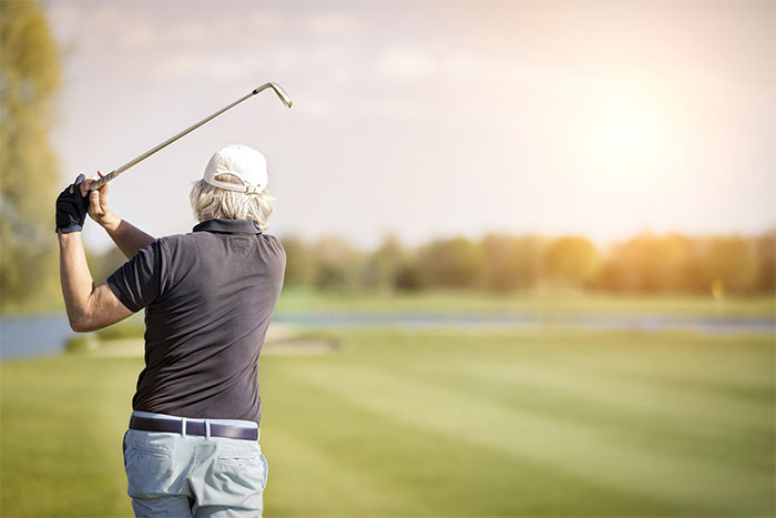 Golfer swings a club over his head